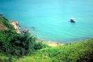 hill slope and blue sea lagoon with small boat seen from hilltop