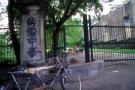 pillar with chinese carven lettering and bicycle, shirtless man in green park area seen through black gate on kim yam road (nan qiao zhong xue (southeast asian overseas chinese middle school))