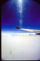deep blue sky above the clouds with airplane wing; sun ray scatter through plane window