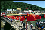 arrival at lamma island: china national flags lining jetty with western commercial signboards