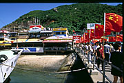 arrival at lamma island: china national flags lining jetty with western commercial signboards: marlboro